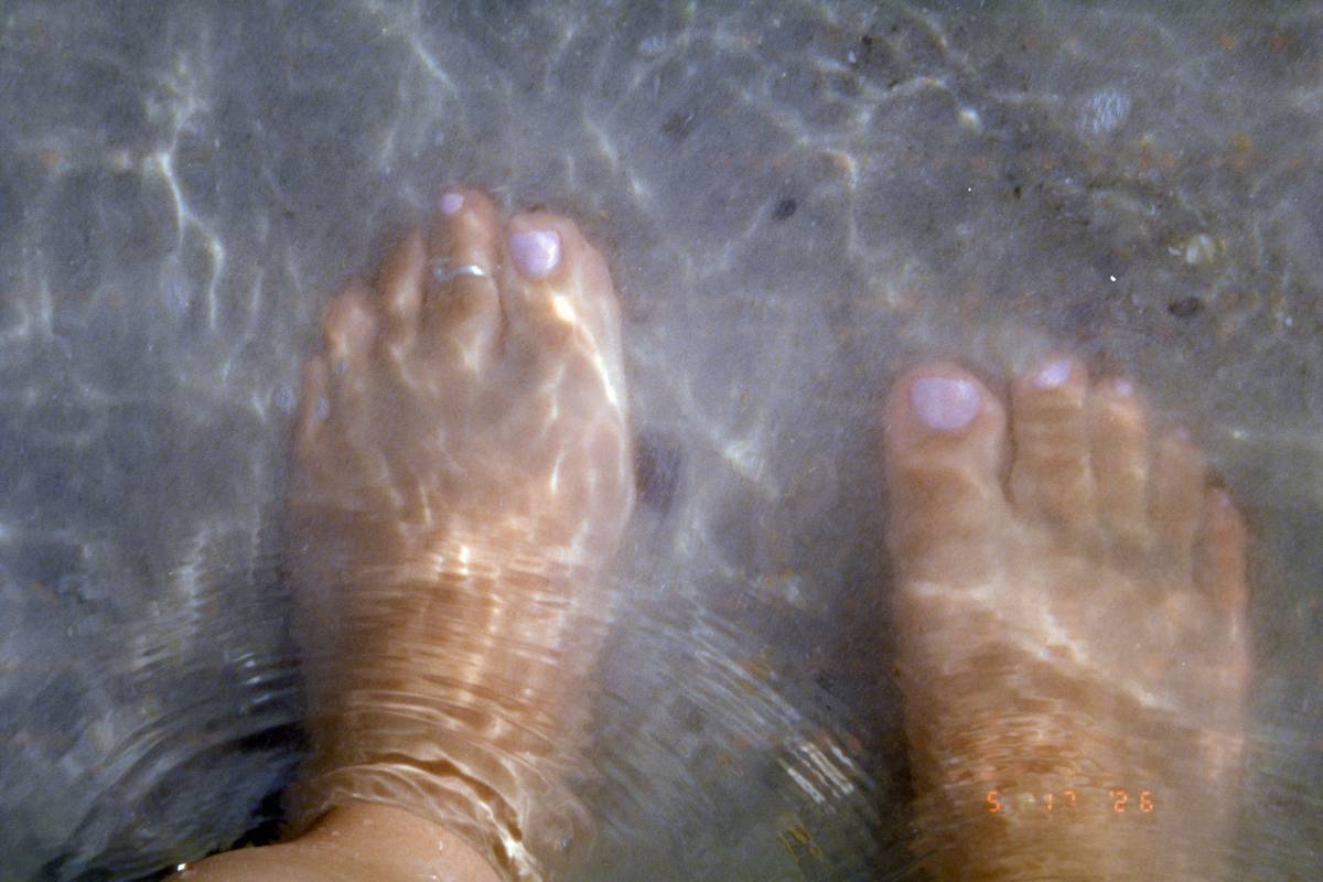 Woman applying hydrating foot mask for dry feet at home, with cream visibly smoothing cracked heels