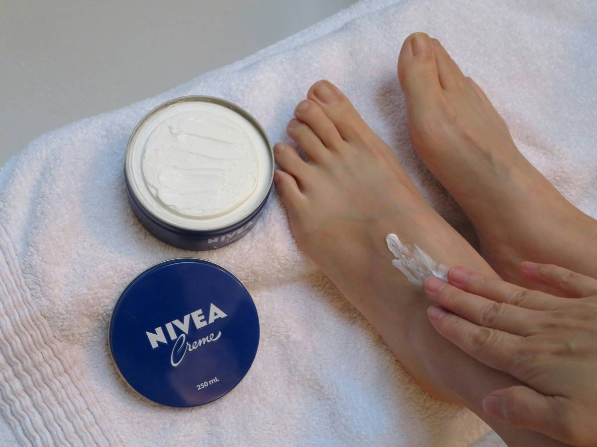 woman applying thick cream foot mask for very dry feet at home